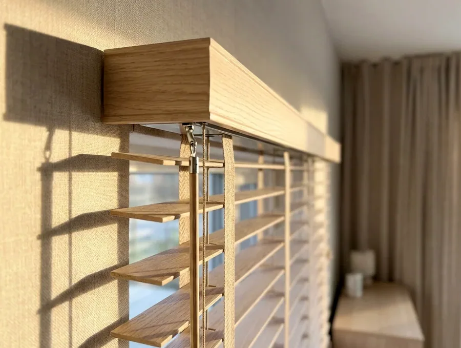 Close view of a timber blind headrail, tilt rod and cords during a repair in a Kyalami home